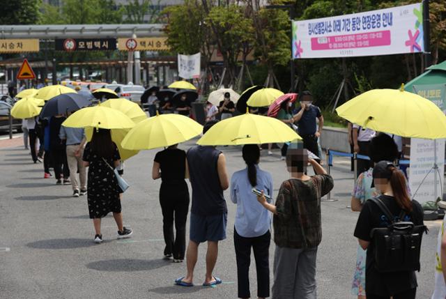 13일 오전 서울 서초구 고속터미널 임시선별검사소에서 시민들이 신종 코로나바이러스 감염증(코로나19) 검사를 받기 위해 대기하고 있다. 노란 양산은 서초구청에서 대여해주는 것으로 대기시간동안 사용 가능하다. 연합뉴스