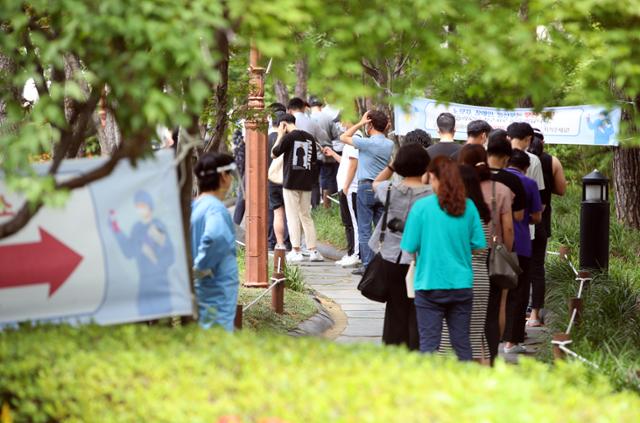 13일 대구 중구 국채보상공원에 마련된 임시선별진료소에서 시민들이 뜨거운 햇볕을 피해 숲길에서 코로나19 검사 순서를 기다리고 있다. 대구=연합뉴스