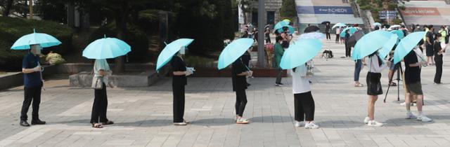 12일 인천 남동구 구월동 한 선별검사소에서 파란 우산을 쓴 시민들이 검사를 기다리고 있다. 인천=연합뉴스