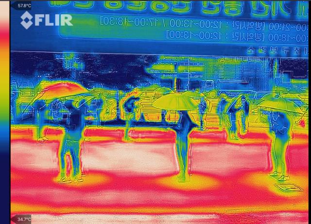 전국적으로 찜통더위가 이어진 14일 오후 서울 서초구 고속버스터미널 광장에 마련된 임시선별검사소에서 서초구가 마련한 양산을 쓴 시민들이 검체 검사를 기다리고 있다. 열화상 카메라로 촬영된 이 사진에서 높은 온도는 붉은색으로, 낮은 온도는 푸른색으로 표시된다. 한편 중앙방역대책본부에 따르면 이날 0시 기준 신규 확진자 수는 지난해 1월 20일 국내에서 첫 코로나19 환자가 발생한 이후 가장 많은 1천615명을 기록했다. 연합뉴스