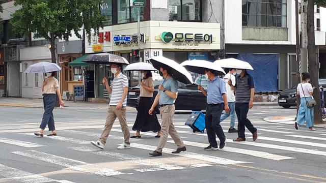 양산을 쓴 직장인들이 15일 대구 도심의 한 횡단보도를 건너고 있다. 중년 남성들의 양산 거부감도 코로나19 사회적 거리두기 덕분으로 많이 줄어들었다. 대구시 제공