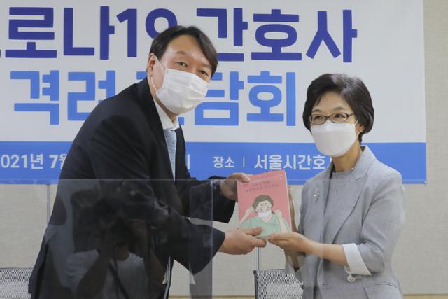 윤석열 전 검찰총장이 22일 서울 구로구 서울시간호사회에서 열린 코로나19 간호사 격려 간담회에서 박인숙 서울시간호사회 회장으로부터 '코로나 영웅, 대한민국을 간호하다' 책을 선물받고 있다. 뉴시스