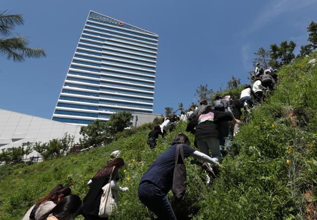 전국민주노동조합총연맹(민주노총)이 원주 집회를 강행한 23일 오후 집회 장소인 강원 원주시 국민건강보험공단 출입이 막히자 노조원들이 인근 수변공원을 우회해 언덕을 넘고 있다. 연합뉴스