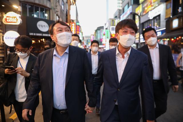 이준석 국민의힘 대표와 윤석열 전 검찰총장이 25일서울 광진구 건대맛의거리에서 '치맥회동'을 마친 뒤 손을 잡고 걷고 있다. 윤석열 캠프 제공