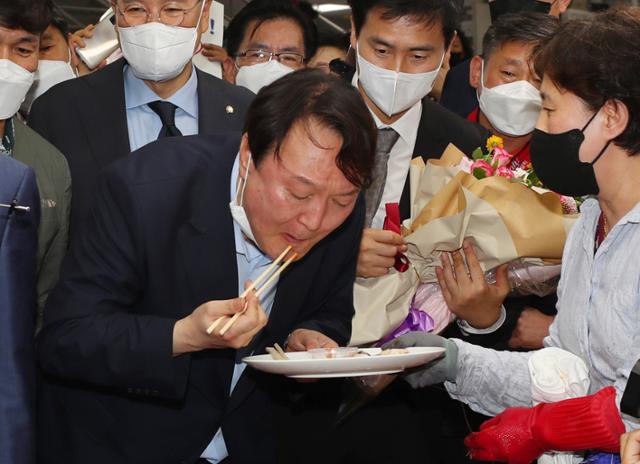 윤석열 전 검찰총장이 27일 오후 부산 중구 자갈치시장을 찾아 상인이 건넨 전복을맛보고 있다. 부산=뉴스1