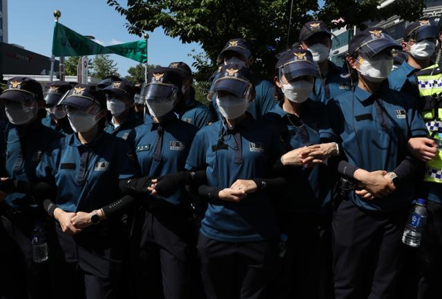 지난달 23일 강원 원주시 국민건강보험공단 인근에서 열린 고객센터 노조 직접 고용 촉구 결의대회에서 경찰이 폭염 속에 건물 출입구를 몸으로 통제하고 있다. 원주= 연합뉴스