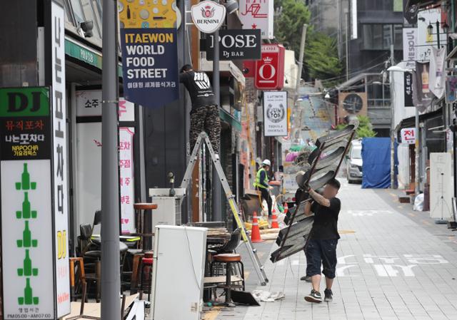 코로나19 4차 대유행이 계속된 19일 서울 이태원의 한 골목에서 폐업 상가 간판이 철거되고 있다. 뉴스1