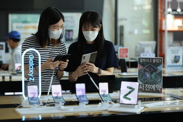 17일 오전 서울 종로구 광화문 kt스퀘어에서 직원들이 삼성전자의 신제품 '갤럭시 Z폴드3'와 '갤럭시 Z플립3'를 살펴보고 있다. 연합뉴스