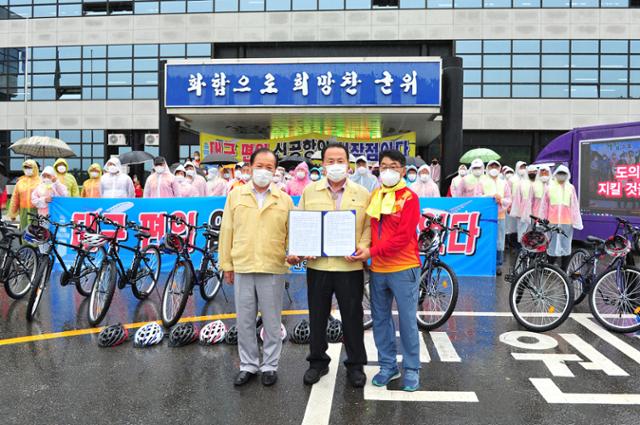 박한배(앞줄 오른쪽)군위군 통합신공항 추진위원장이 23일 오후 군위군청 앞에서 김영만(가운데) 군수와 심 칠(왼쪽) 군위군의장에게 ‘군위군 대구 편입 찬성촉구 성명서’를 발표한 뒤 전달했다. 박 위원장 등은 이날 아침부터 자전거를 타고 대구 편입을 촉구하며 읍면을 순회했다. 군위군 제공