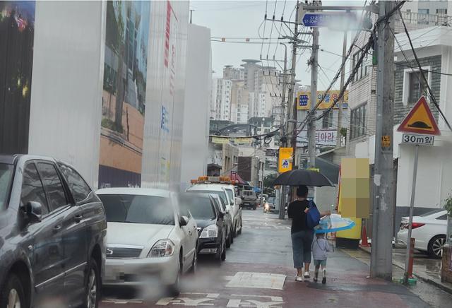 대형 건설사 S건설이 공사현장 옆 어린이보호구역 보행자 안전을 위협한다는 지적이 일고 있다. 25일 오전 9시 한 모자가 보행로도 없는 도로를 걸어 유치원으로 가고 있다. =김민규 기자 whitekmg@hankookilbo.com