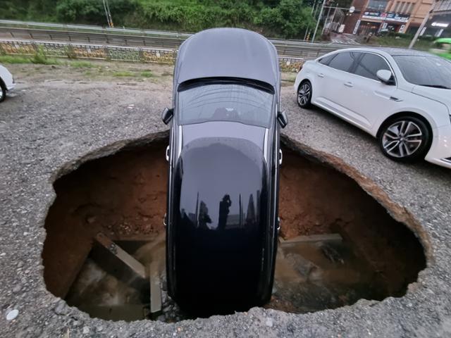 1일 오전 충남 당진시 시곡동의 한 주차장에서 지반침하로 생긴 구덩이에 차량 1대가 빠져있다. 당진소방서 제공