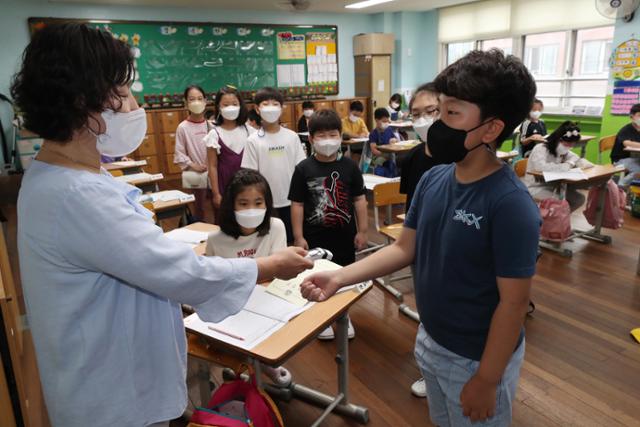 2학기 등교가 확대된 6일 오전 대전 서구 둔산초등학교 3학년 교실에서 담임교사가 학생들의 체온을 재고 있다. 뉴스1