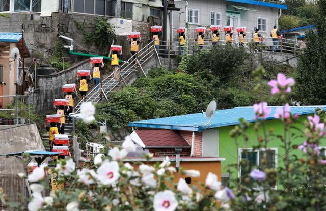 13일 부산 연제구 물만골 마을 주택가에서 부산 적십자 봉사원들이 추석을 앞두고 이웃에게 전달할 구호품을 들고 골목길을 오르고 있다. 연합뉴스