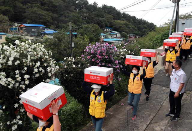 13일 부산 연제구 물만골 마을 주택가에서 부산 적십자 봉사원들이 추석을 앞두고 이웃에게 전달할 구호품을 들고 골목길을 오르고 있다. 연합뉴스