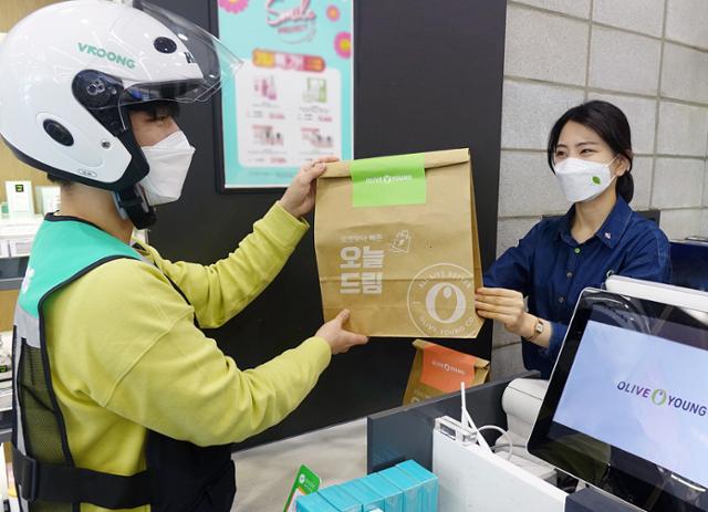 CJ올리브영 배달기사가 매장 직원으로부터 고객에게 배송할 화장품을 넘겨받고 있다. 3시간 이내 배송인 '빠름배송'은 올 상반기 평균 45분 이내로 배송을 완료한 것으로 확인됐다. 지난해 평균 55분에서 10분가량 줄어든 수치다. CJ올리브영 제공