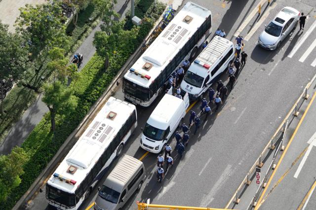 파산 위기에 몰린 중국 부동산 개발업체 헝다그룹의 광둥선 선전 본사 주변에서 24일 공안들이 줄을 지어 차량 옆을 지나가고 있다. 선전=AP 연합뉴스