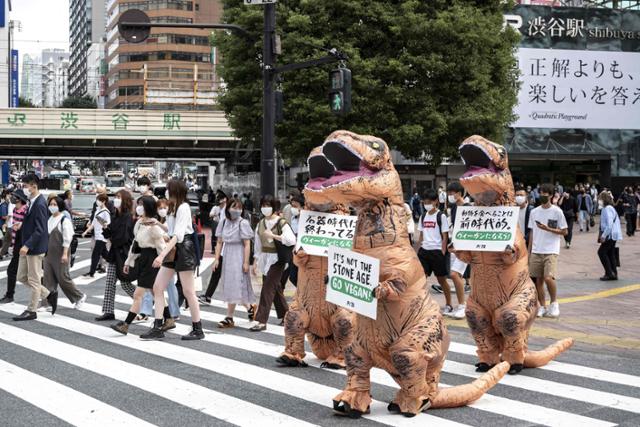 국제동물보호단체 페타(PETA.동물의 윤리적 처우를 지지하는 사람들) 회원들이 6일 일본 도쿄 거리에서 공룡 모습의 복장을 한 채 시민들에게 채식주의자(비건)가 될 것을 촉구하고 있다.도쿄 AFP=연합뉴스