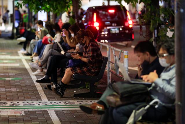 7일 밤 일본 수도권에 발생한 강한 지진의 영향으로 열차 운행이 중단되자 귀가 수단이 끊긴 도쿄 시민들이 역 밖에서 열차 운행이 재개되길 기다리며 스마트폰으로 뉴스 속보를 보고 있다. 도쿄=AP 연합뉴스