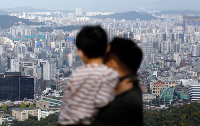 11일 서울 남산에서 한 남성이 아이를 안고 도심을 바라보고 있다. 뉴시스