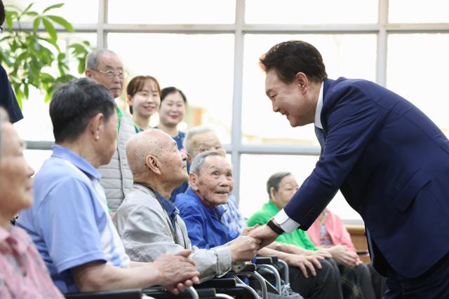 윤석열 대통령이 21일 경기 수원 장안구 수원보훈요양원을 방문해 단체 기념촬영에 앞서 입소자들과 인사를 나누고 있다. 대통령실 제공