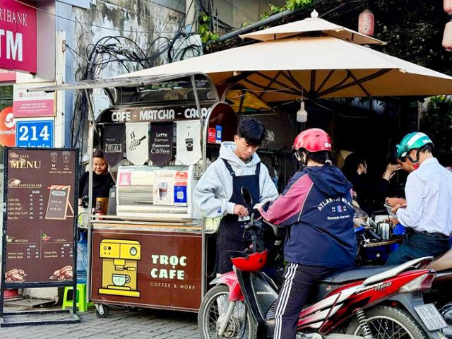 Commuters stop to buy coffee on their motorbikes during the morning commute in Ho Chi Minh City, Vietnam. Hankook Ilbo