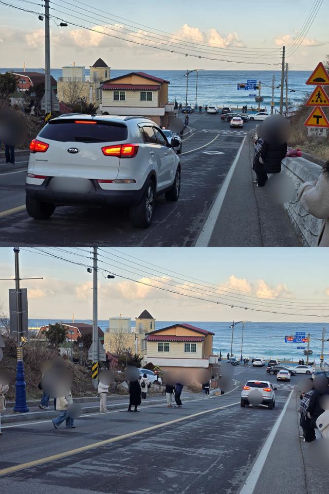 Visitors at Eodal Samgeori in Donghae, Gangwon Province, step aside briefly for passing cars before moving back into the roadway to take photos on Feb. 7. Korea Times photo by Shin Eun-byul