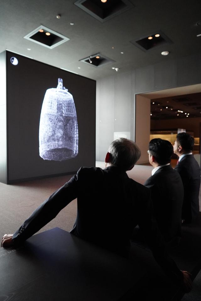 National Museum of Korea Director Yoo Hong-jun, left, and HYBE Chairman Bang Si-hyuk, center, listen to the sound of the Sacred Bell of Great King Seongdeok at the sensory exhibition hall of the National Museum of Korea in October 2025. Courtesy of the National Museum of Korea