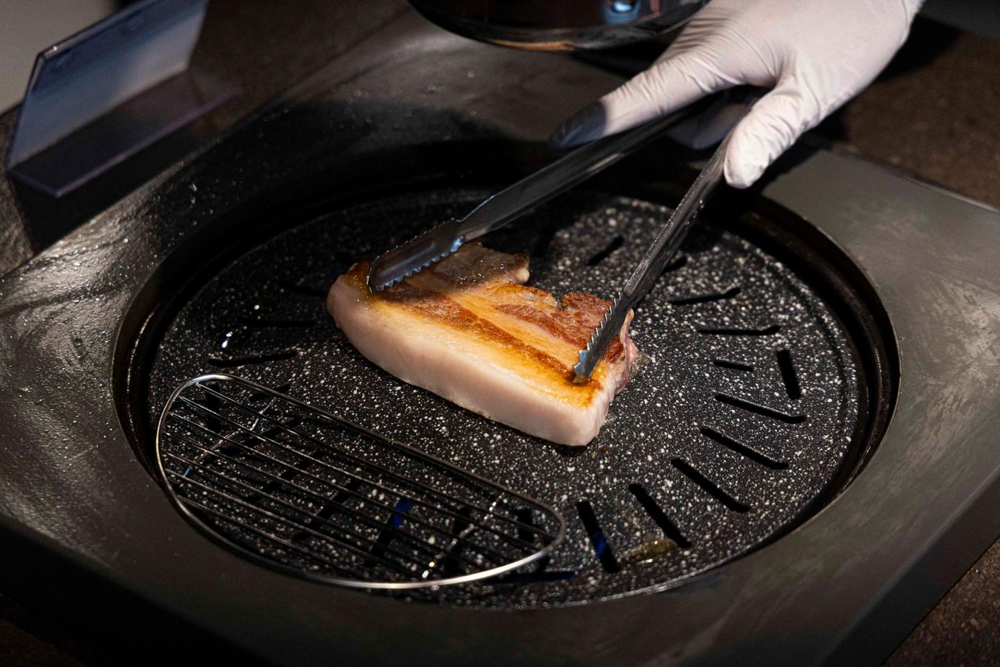 Cha Ho-myung demonstrates how to grill samgyeopsal, or pork belly, according to Sunjin's grilling manual during the 19th Grilling Meister certification exam on Oct. 14. Cha says factors including the temperature of the grill and meat, the thickness of the pork, cooking time and even the color of the rendered fat should be checked. Courtesy of Sunjin